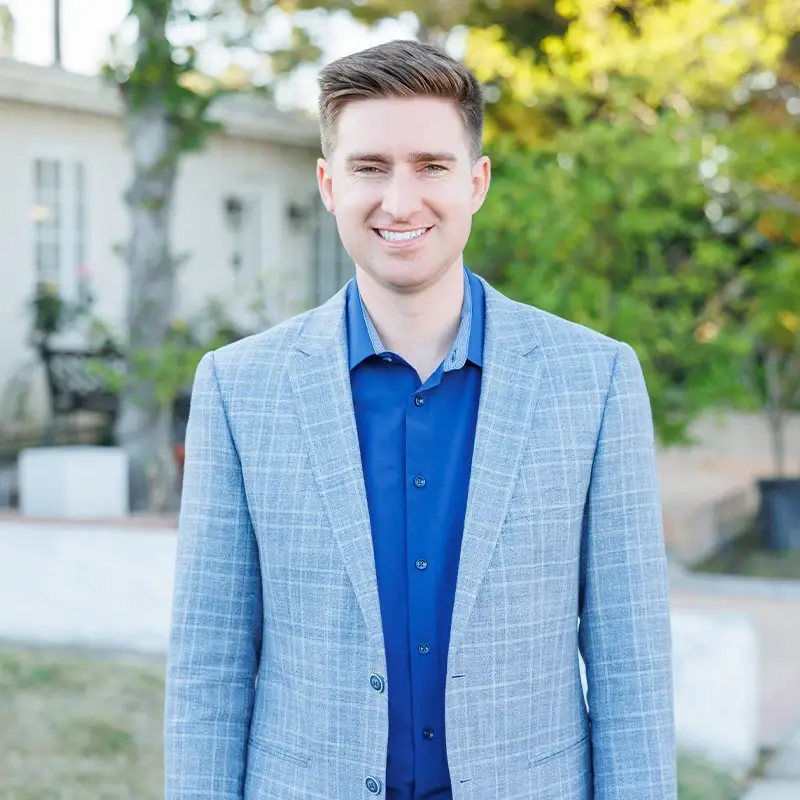 Connor Traut smiling in front of a residence and tree.