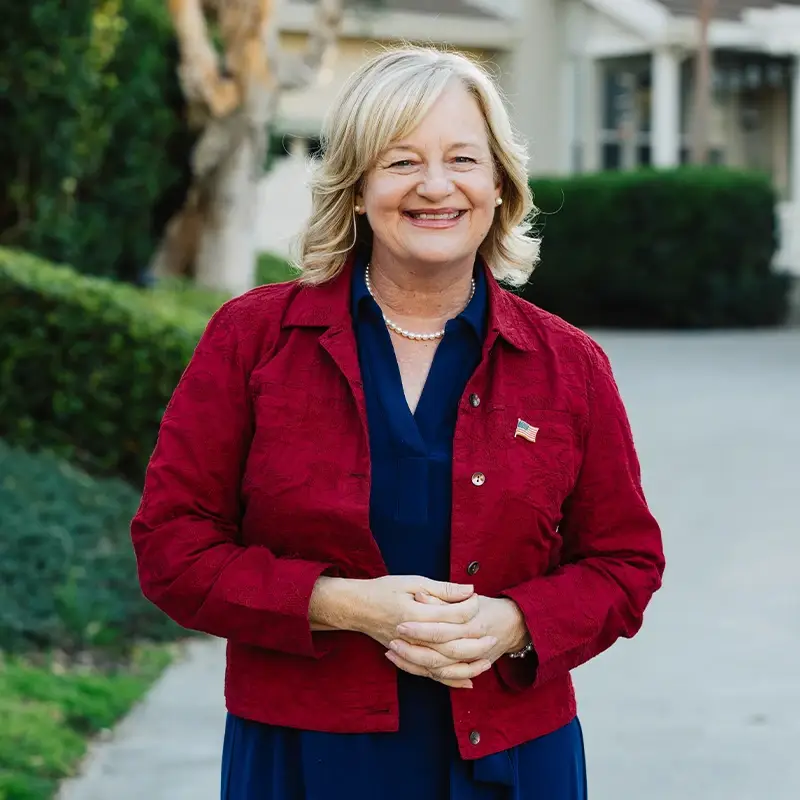 Katrina Foley smiling in front of a house and driveway.