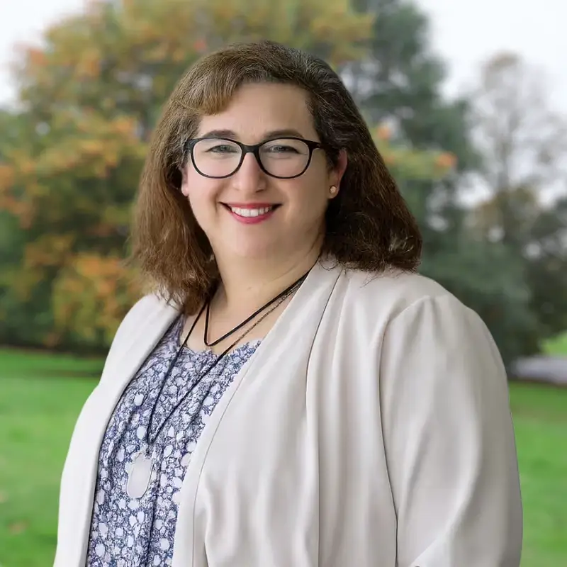 Dr Shana Charles smiling in front of a park-like background.