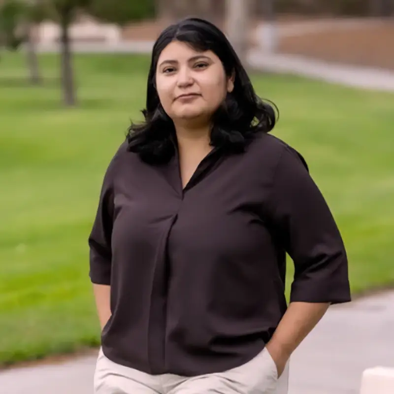 Sandra de Anda leaning against a bench in front of a park.